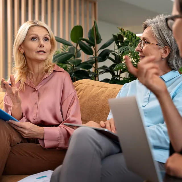 Drei Damen auf einer Couch sitzend und unterhalten sich