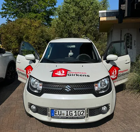 Team-Foto. Zwei Damen lächeln aus dem Pflege-Auto heraus.